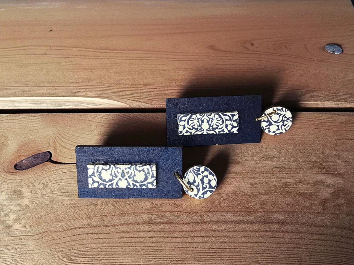 Pair of earrings with decorative boxes on a wooden surface