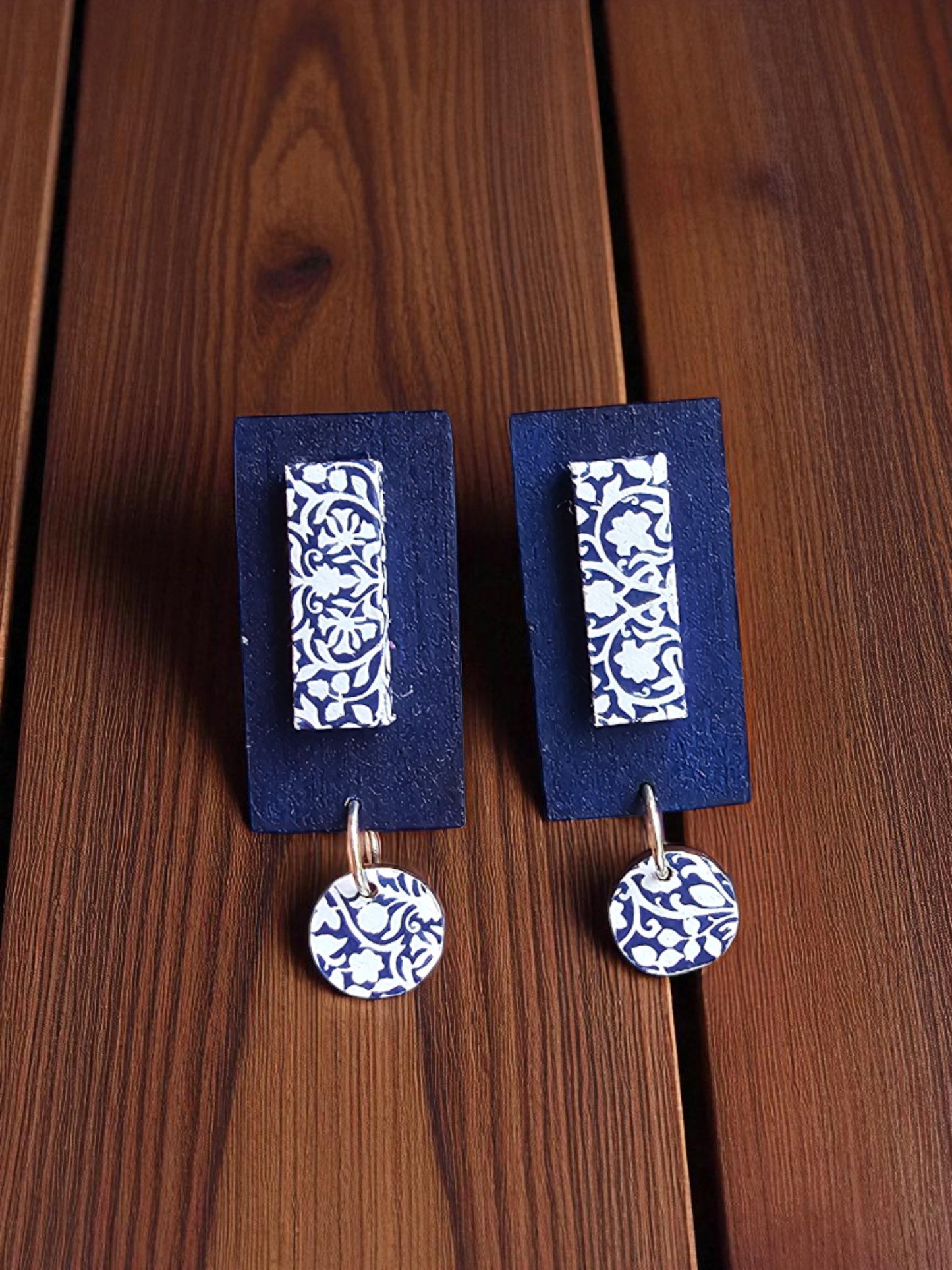 Pair of blue and white patterned earrings on matching display cards against a wooden background