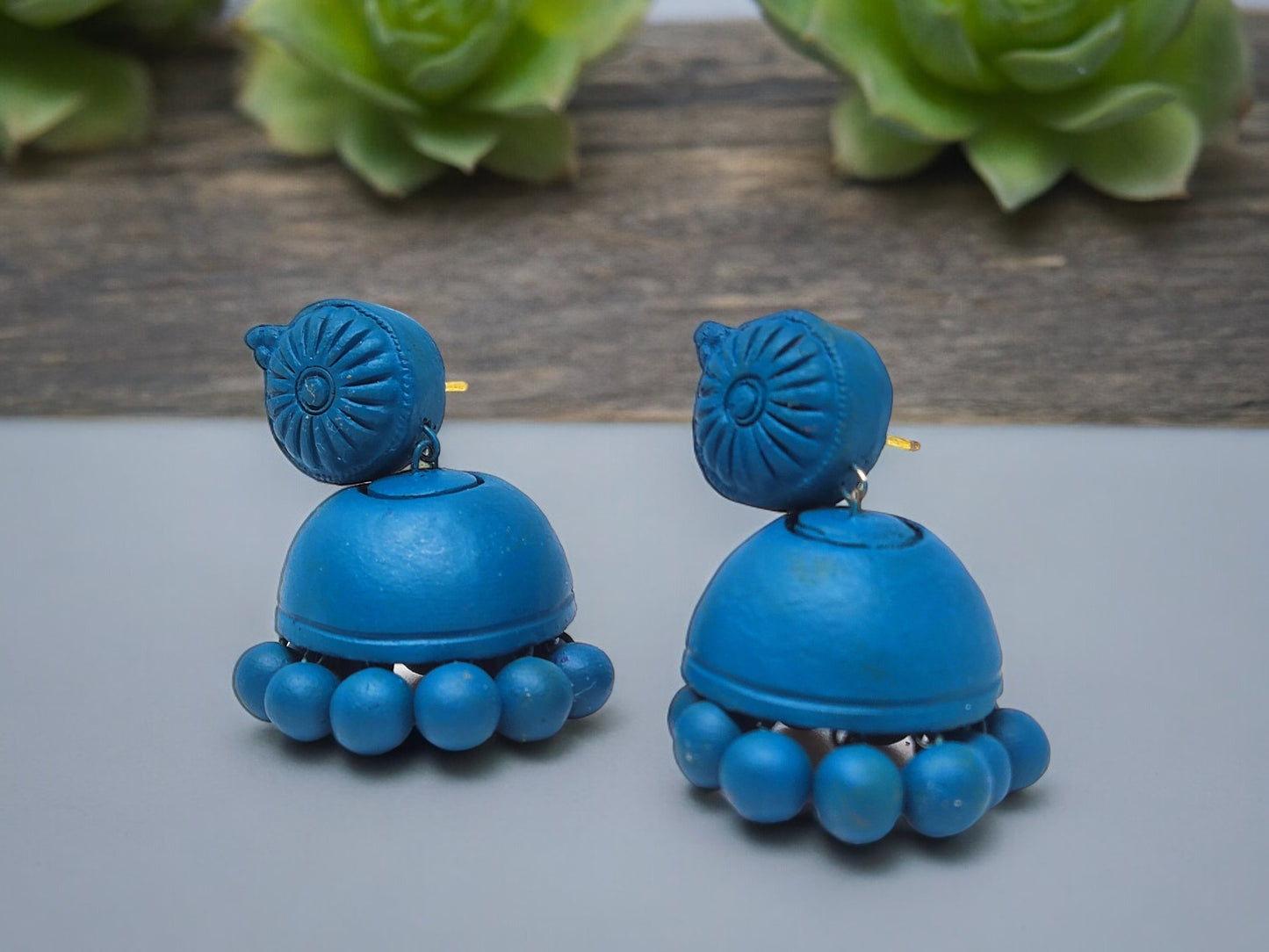 Peacock blue terracotta earrings from Anusangi Collections with round bead detailing and floral top design