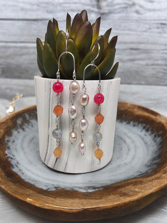Artisan sterling silver earrings with colorful beads and pearls displayed on a white marble pot