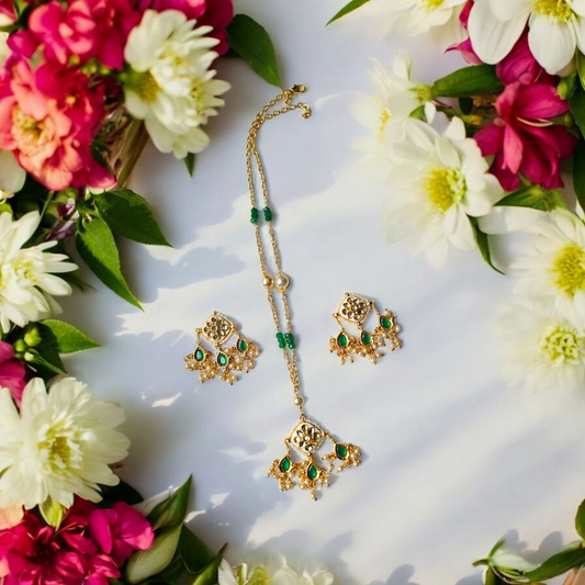 Bani anti tarnish necklace and earrings from Anusangi Collections with green beads and gold detailing surrounded by flowers