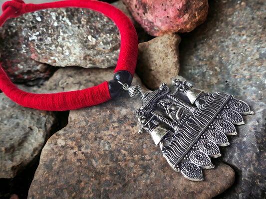 Brass necklace set with silver details featuring a red thread and intricate traditional pendant design