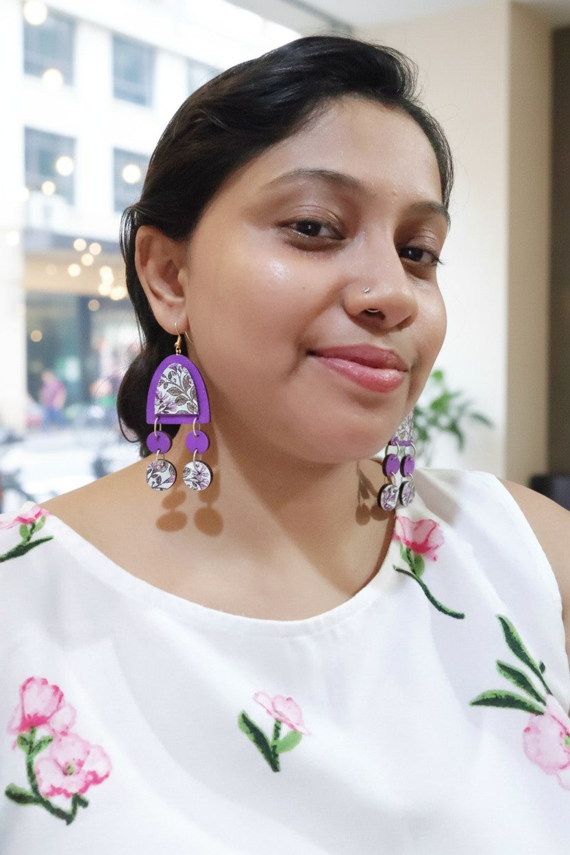 Woman wearing botanic charm earrings handmade paired with a matching necklace and a floral top