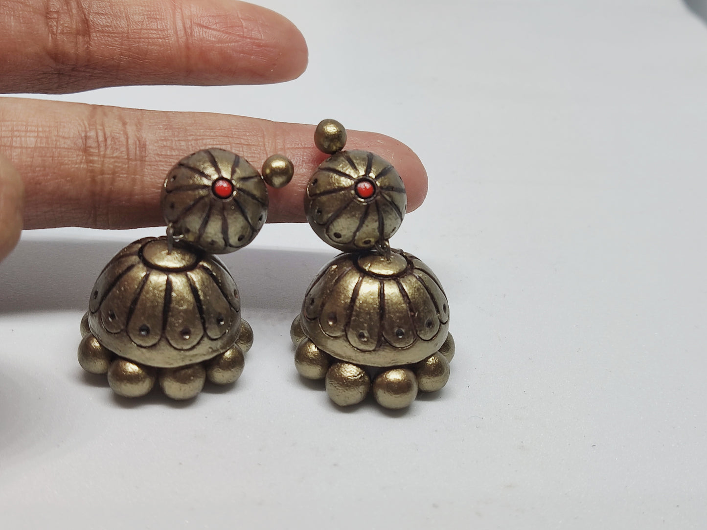 Buy Rachana Terracotta Jhumka online from Anusangi Collections with antique gold finish and red bead detail