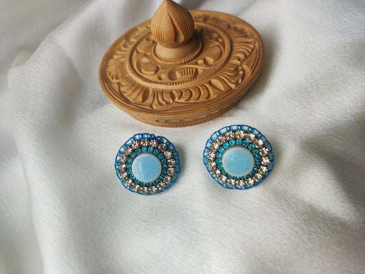 Anusangi Collections colorful embroidered earrings with blue and silver beaded design on white fabric
