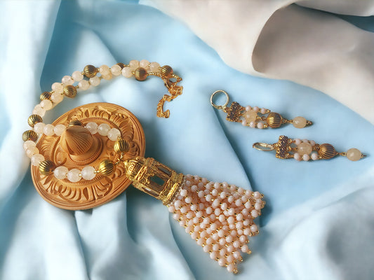 Darika necklace and earrings set from Anusangi Collections featuring cream beads and gold accents on light blue fabric