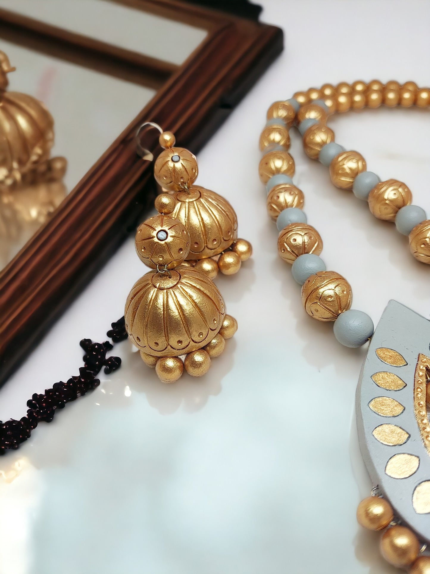 Gold and gray jewelry set from Anusangi Collections featuring terracotta necklace and earrings