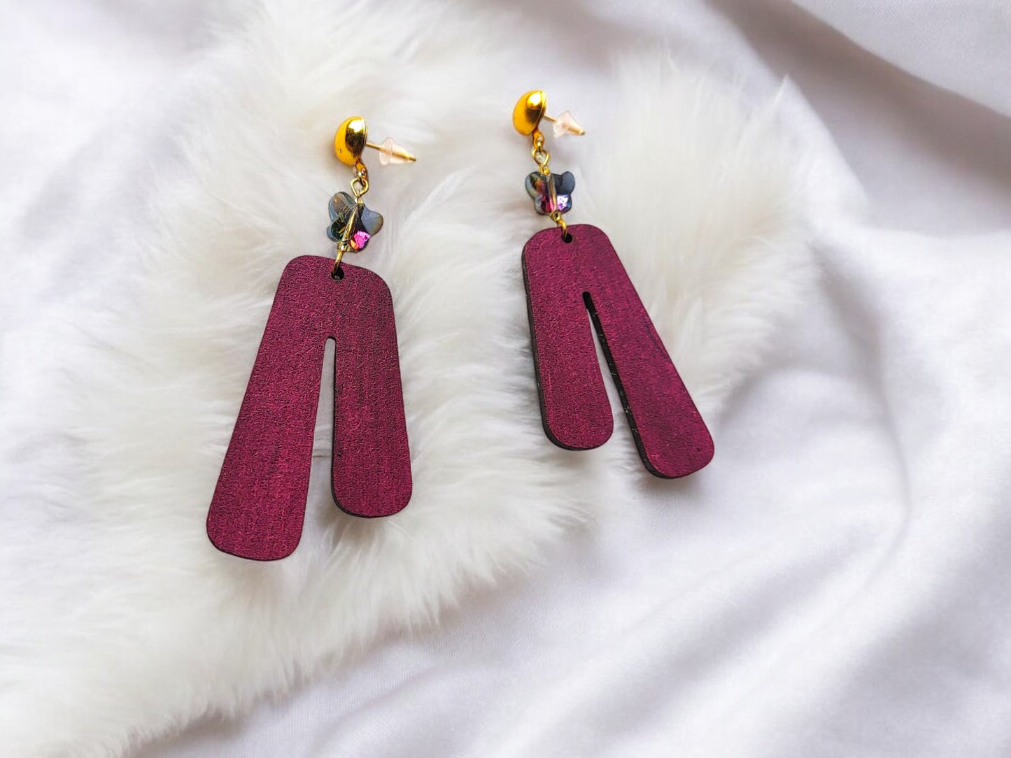 Anusangi Collections purple wooden earrings with gold hooks and decorative beads on white fabric