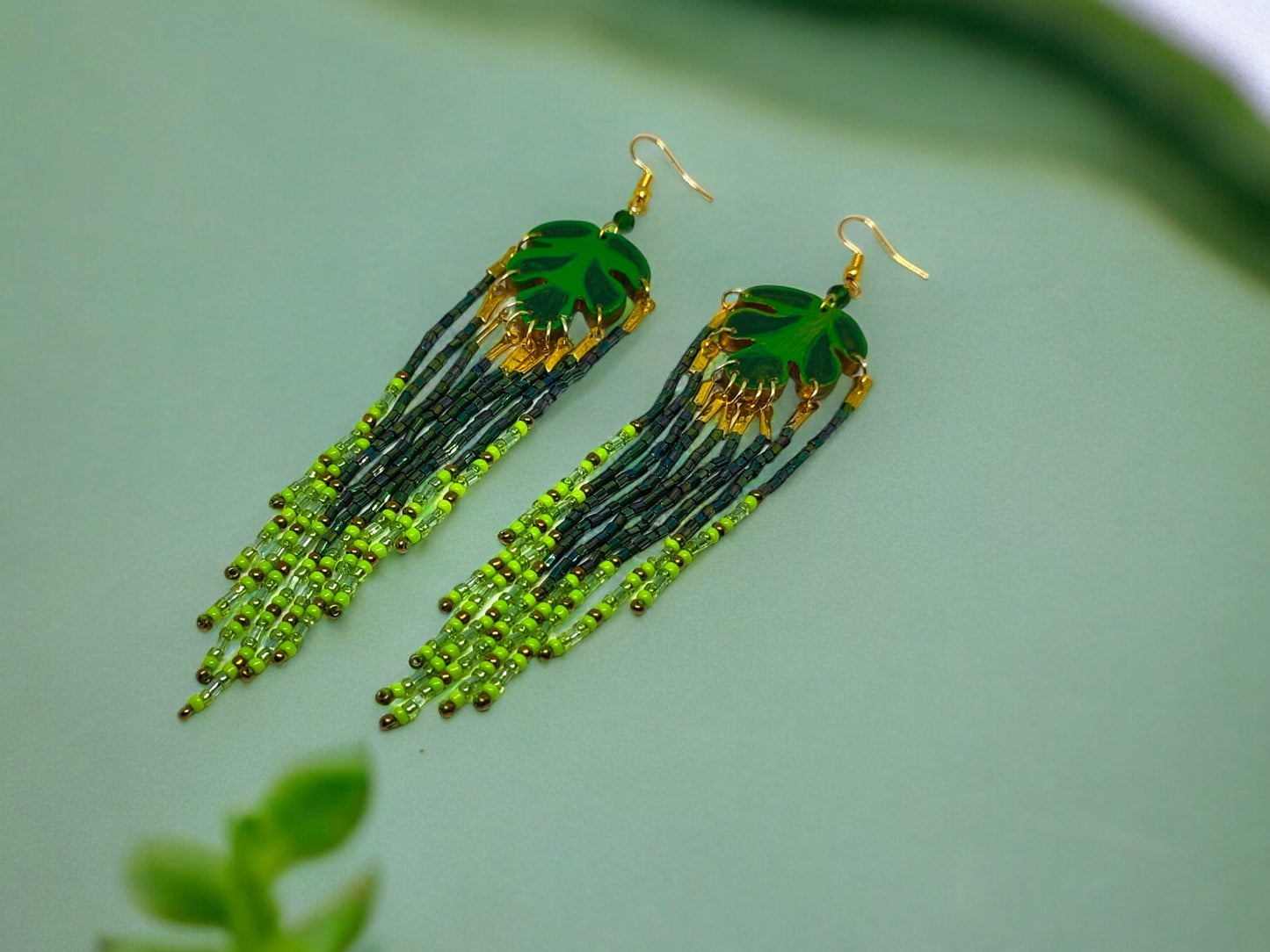 Green leaf beaded earrings with intricate gold accents and hanging seed beads from Anusangi Collections