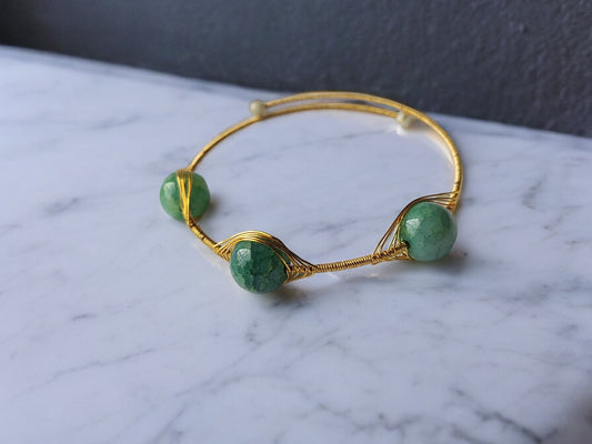 Anusangi Collections green stone bangle bracelet with gold wire and three green stones on marble surface