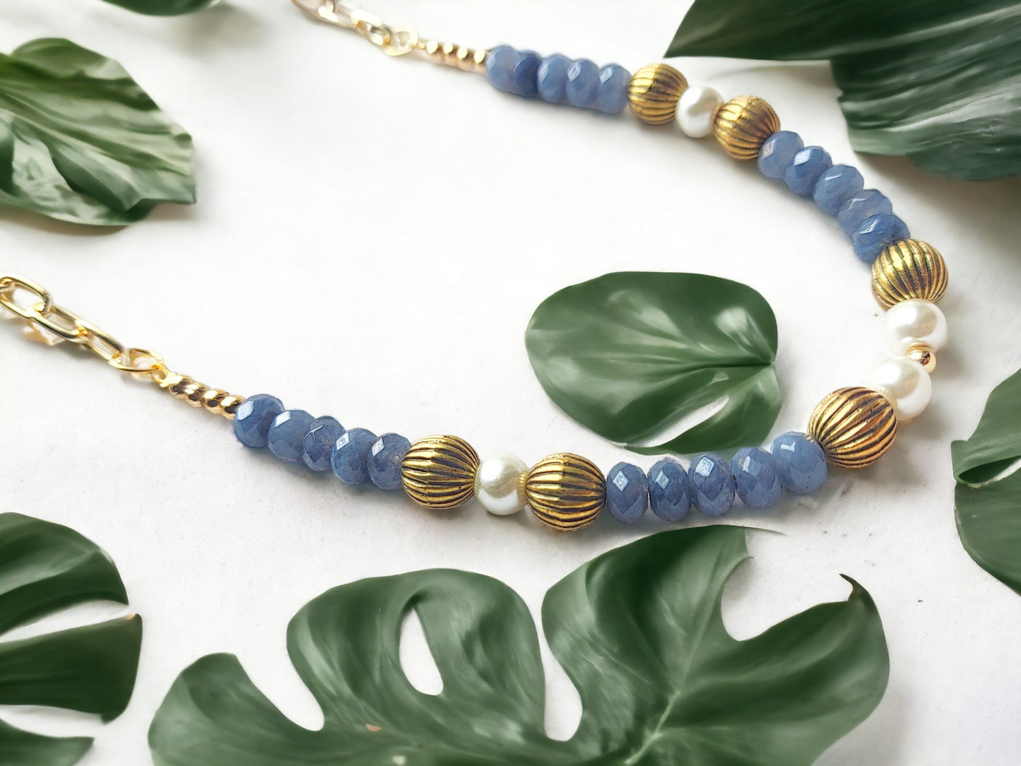 Grey bead necklace gold accents featuring unique blue and white beads with elegant gold details
