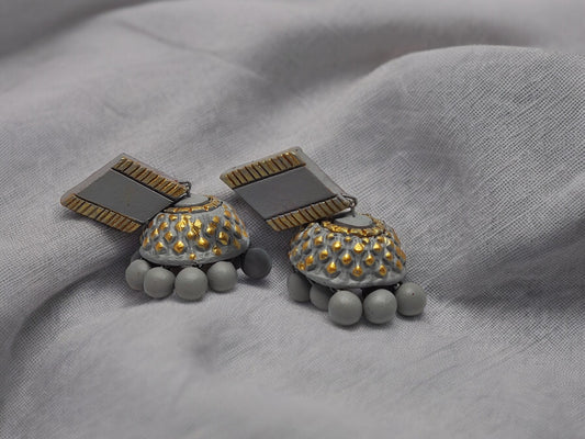 Anusangi Collections grey terracotta earrings with gold accents and round beads on grey fabric