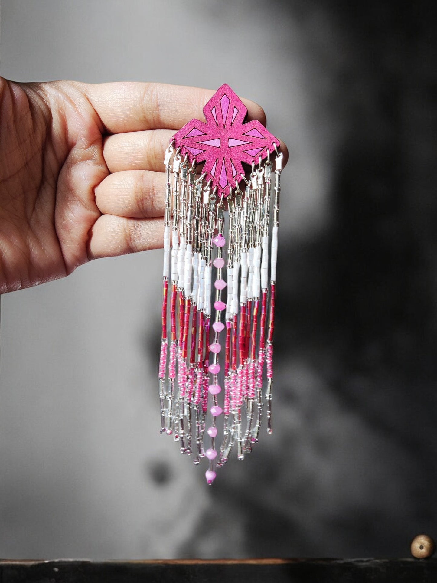 Pink and white beaded long earrings with intricate design from Anusangi Collections held in hand
