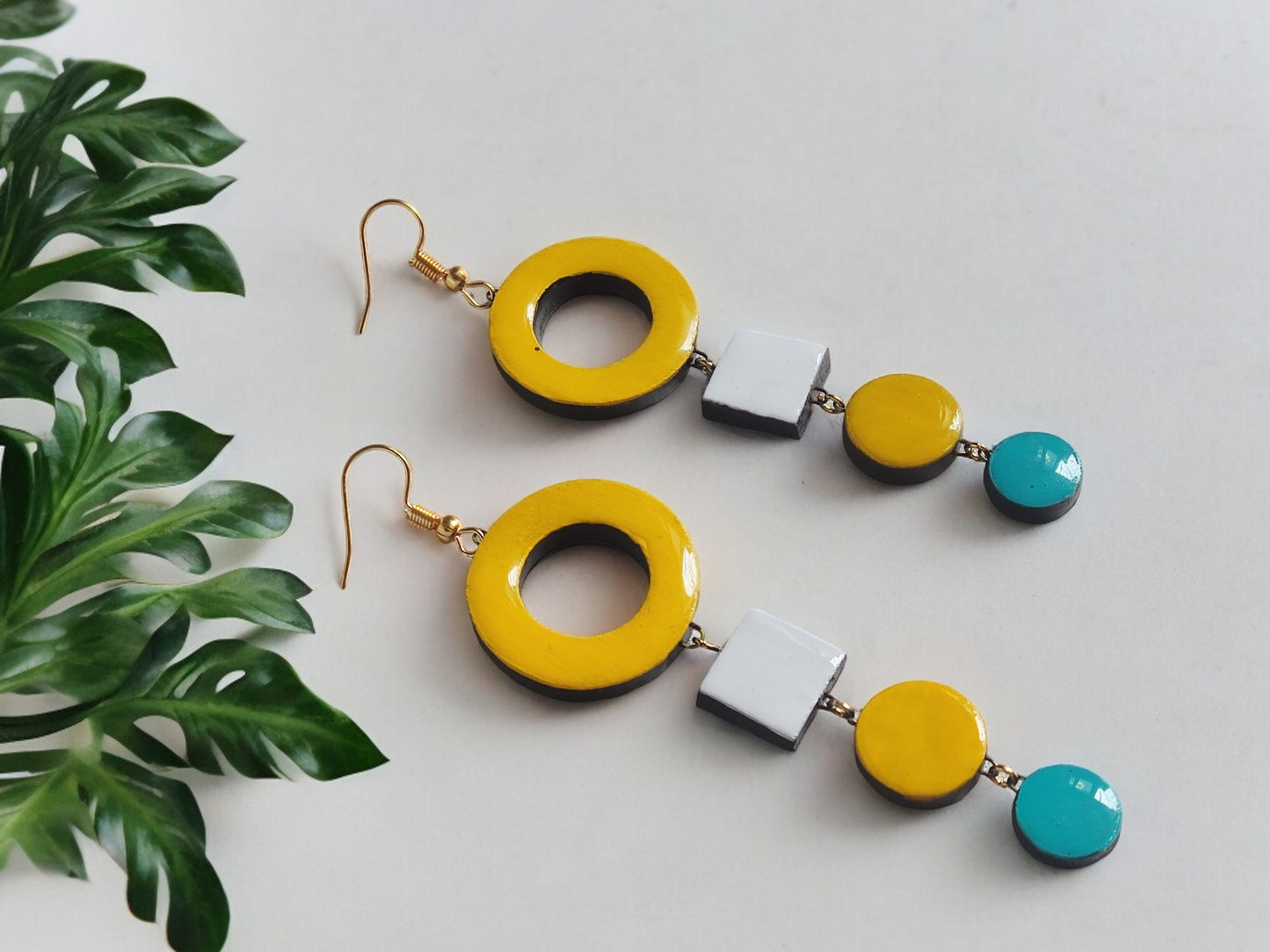 Anusangi Collections handmade terracotta earrings with yellow, white, and blue geometric shapes