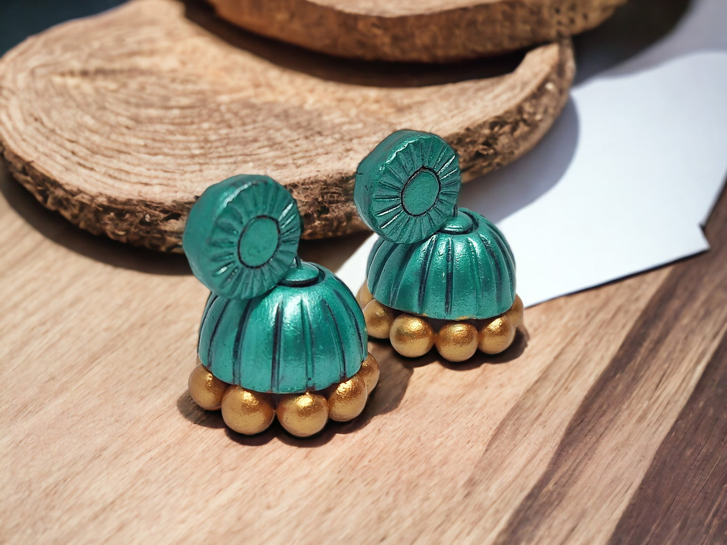 Handmade Terracotta jhumka earrings in teal and gold from Anusangi Collections on wooden surface