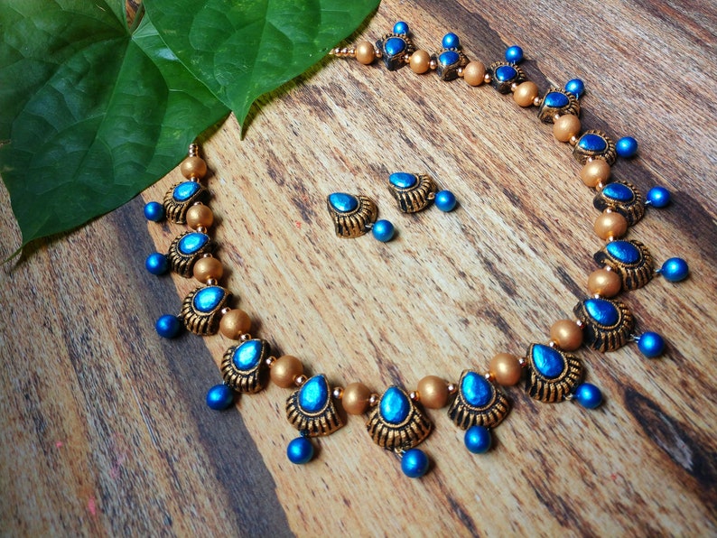 Anusangi Collections Ocean Blue Carapace Necklace terracotta jewelry set with matching earrings on wooden surface