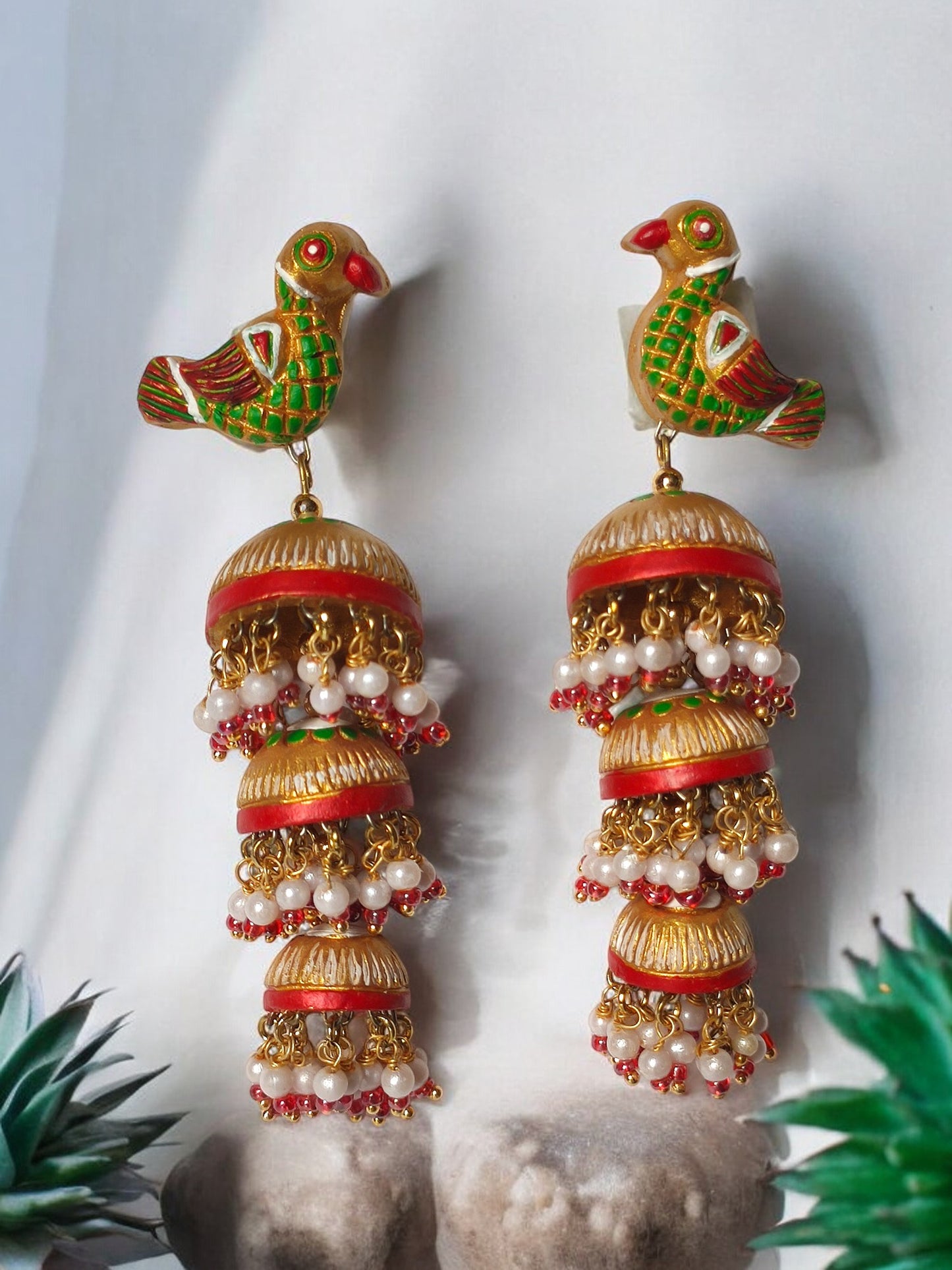Anusangi Collections parrot motif terracotta jhumka earrings with green and red accents and pearl tassels