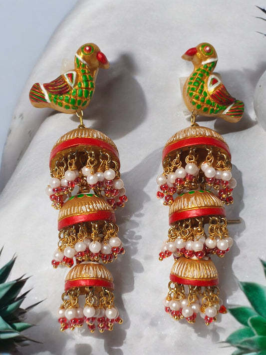 Anusangi Collections parrot motif terracotta jhumka earrings with intricate green and red detailing and pearl embellishments