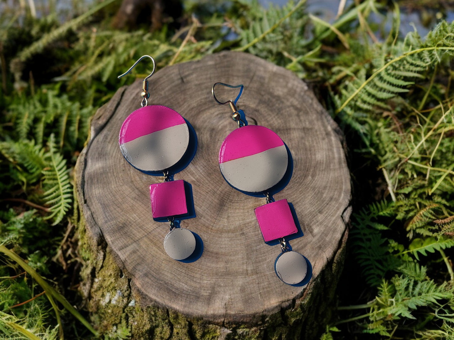 Anusangi Collections terracotta pink and gray statement earrings displayed on wood with greenery background