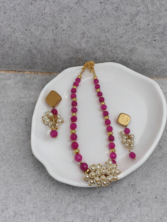 Pink and pearl necklace earrings set with gold accents on white dish by Anusangi Collections
