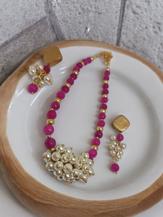 Pink and pearl necklace earrings set from Anusangi Collections featuring gold accents on white plate