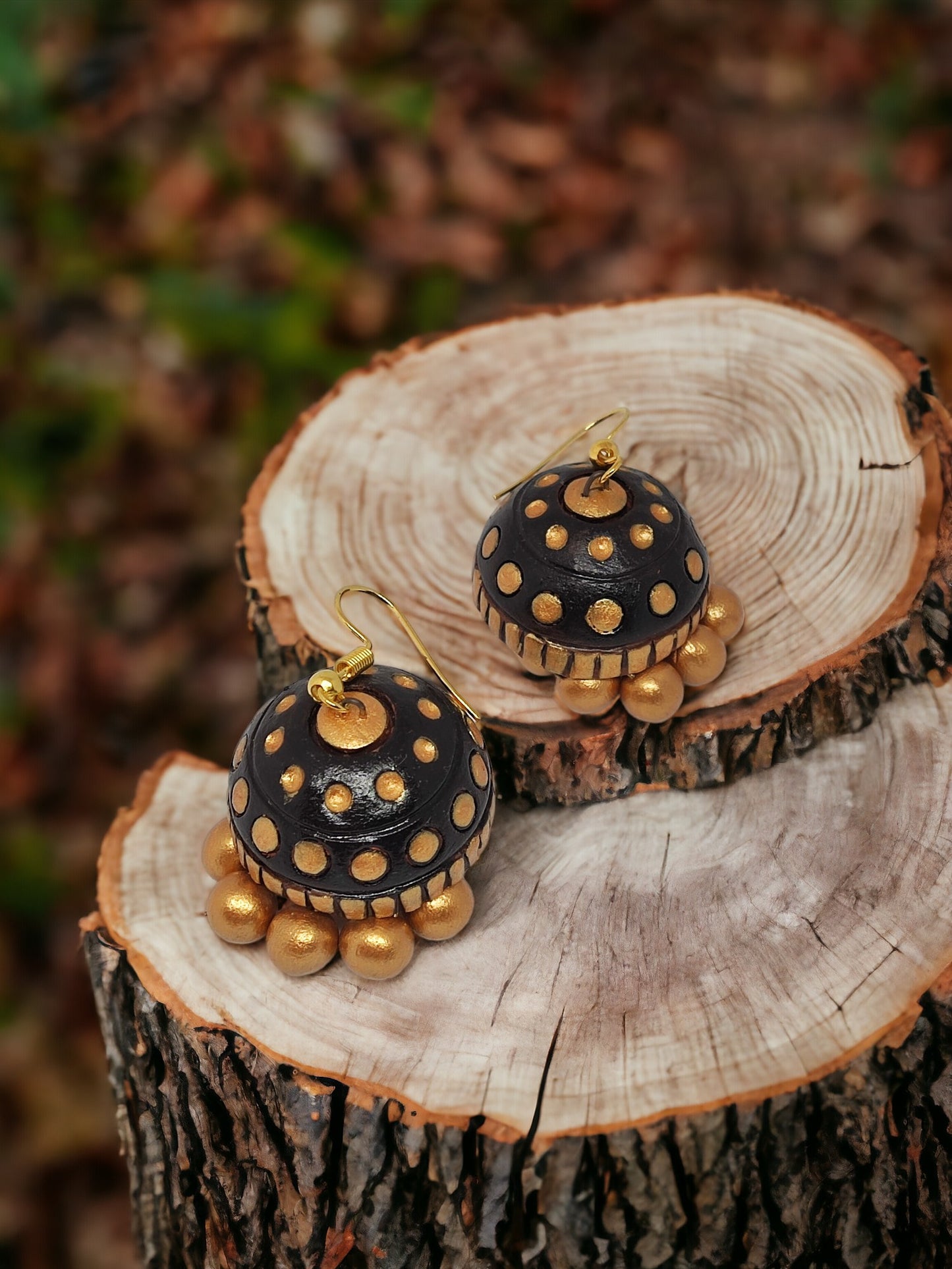 Rambha Jhumka Terracotta Earring black and gold design displayed on wooden surface by Anusangi Collections