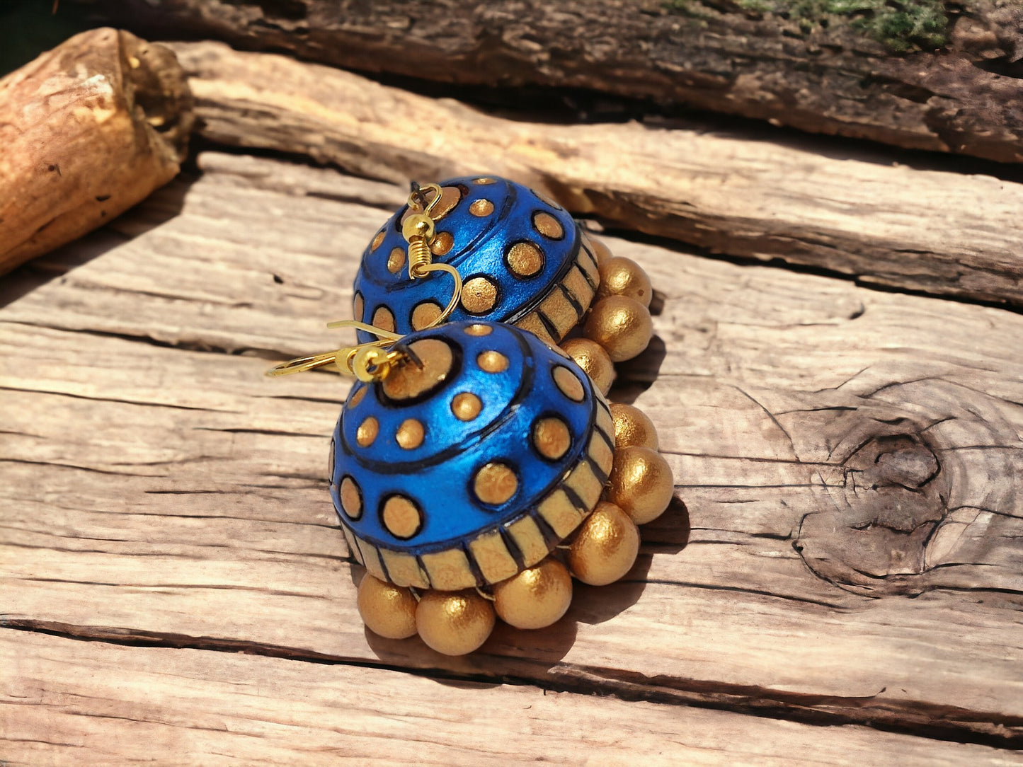 Rambha Jhumka Terracotta Earring in blue and gold, handcrafted by Anusangi Collections on wooden background