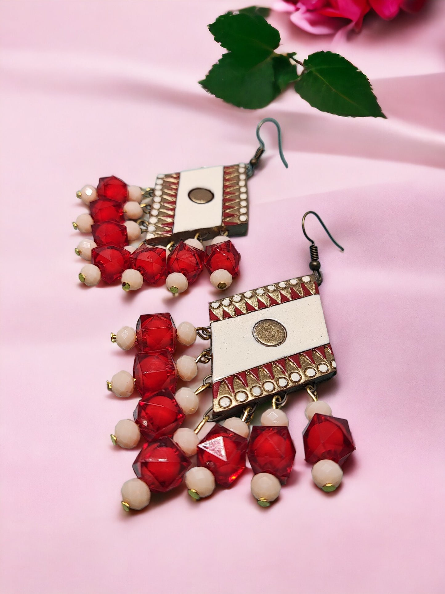 Anusangi Collections red terracotta earrings with white and gold accents on pink background