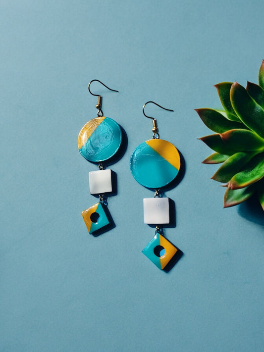 Anusangi Collections fancy terracotta jewelry with blue and yellow geometric earrings on blue background