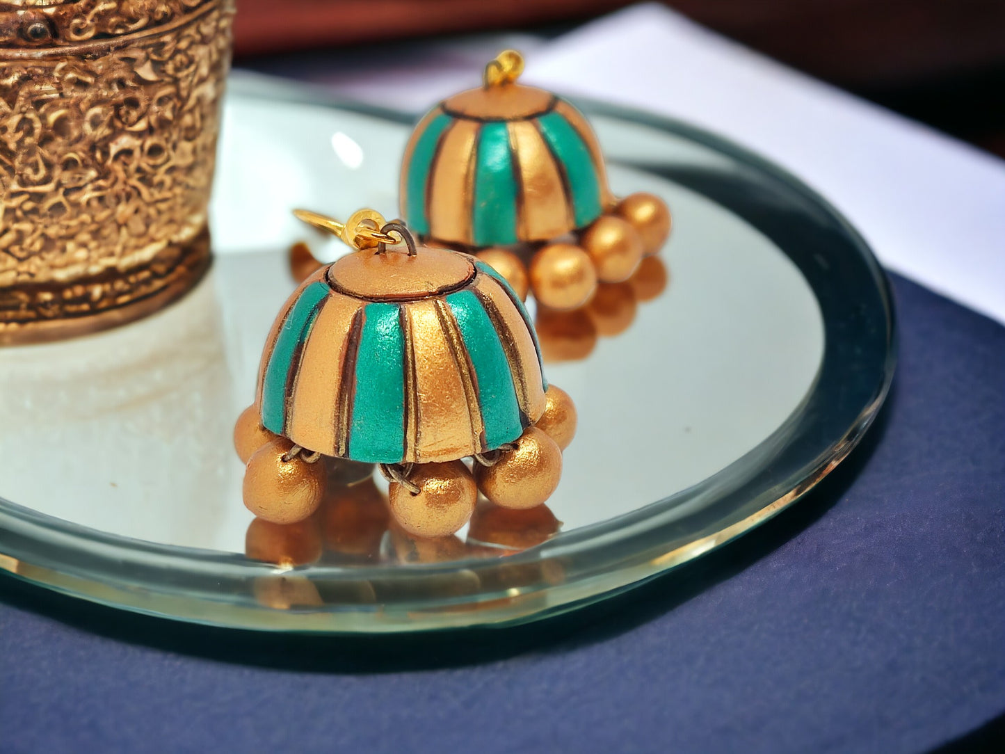 Anusangi Collections Saumya terracotta jewelry blue and gold jhumka earrings on glass plate