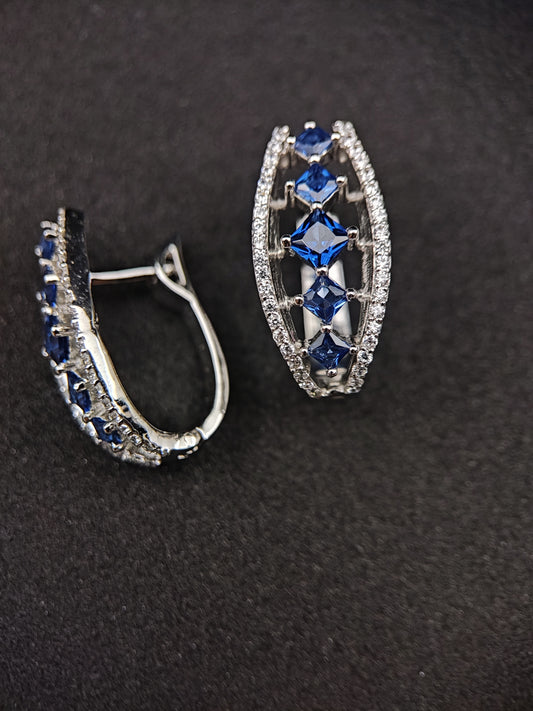 Anusangi Collections sterling silver earrings with blue stones and clear accents on black background