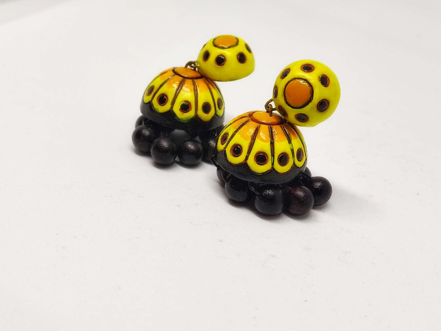Yellow and black Titli terracotta jhumka earrings from Anusangi Collections with intricate dot patterns