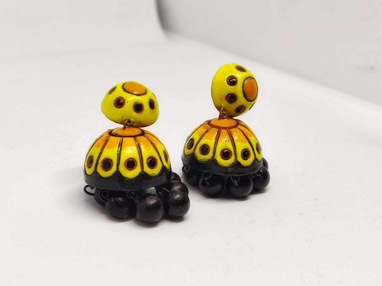 Yellow and black Titli terracotta jhumka earrings from Anusangi Collections with intricate hand-painted design