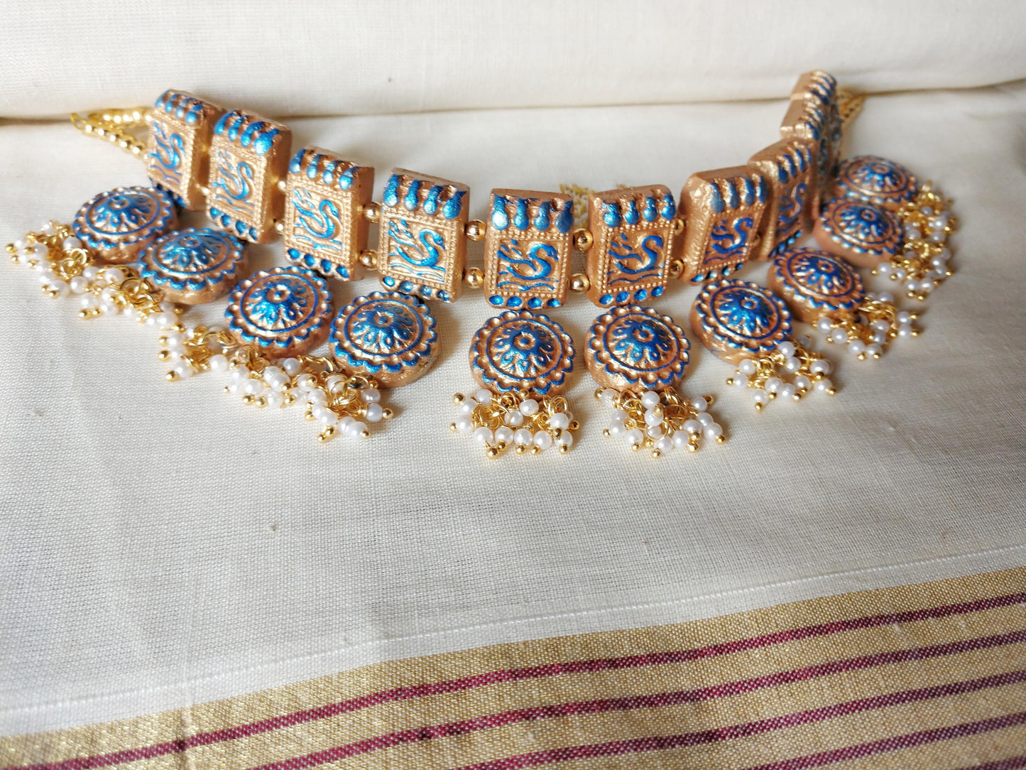 Anusangi Collections terracotta jewelry set featuring a traditional fabric choker necklace with blue and gold detailing