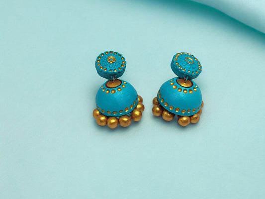 Turquoise blue terracotta earrings with gold accents from Anusangi Collections on light blue background
