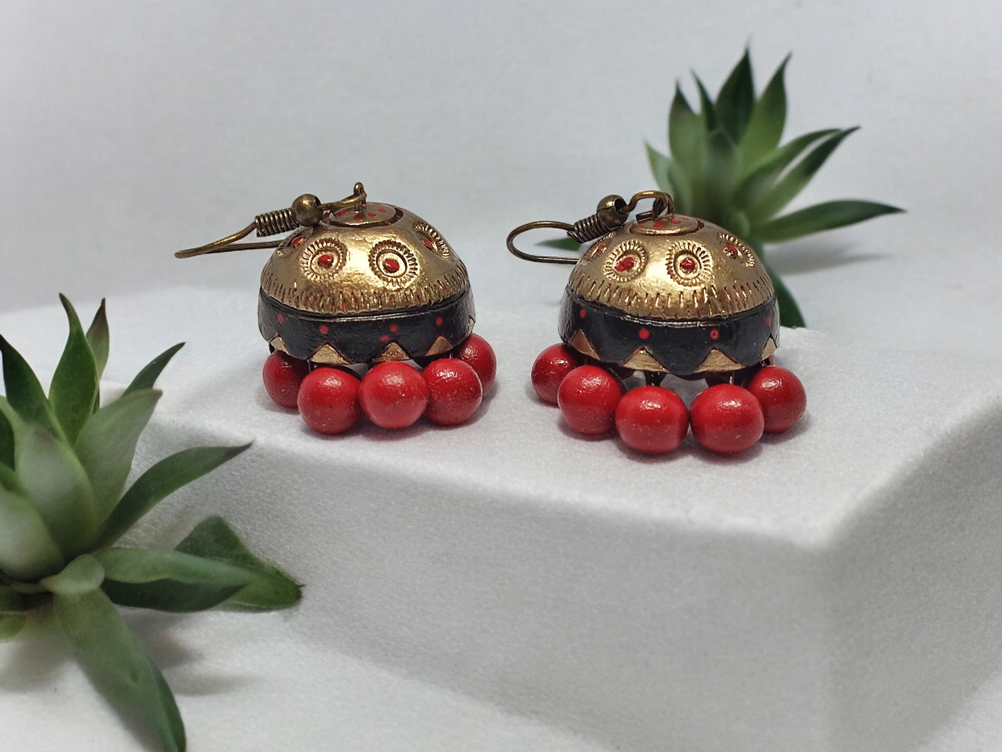 Anusangi Collections Vaidehi terracotta earrings with gold and red bead detailing on white platform