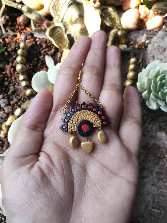 Varenya Terracotta necklace and earrings set pendant with intricate red and gold design held in hand