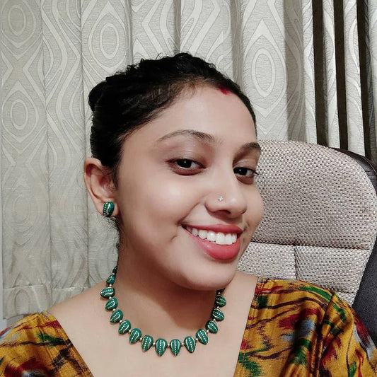 Woman wearing Varka terracotta jewelry set featuring green bead necklace and matching earrings from Anusangi Collections