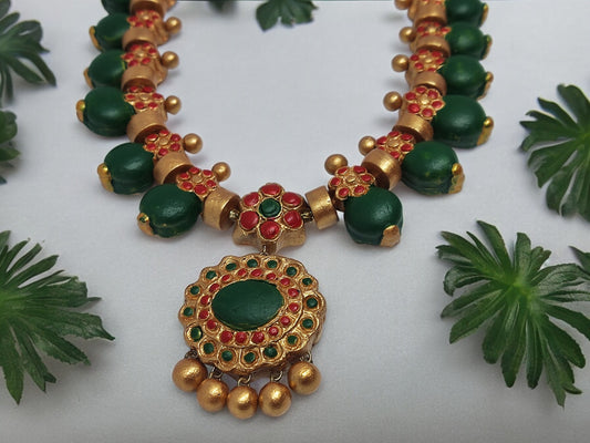 Grand terracotta necklace and earrings with green and red beads and gold accents from Anusangi Collections