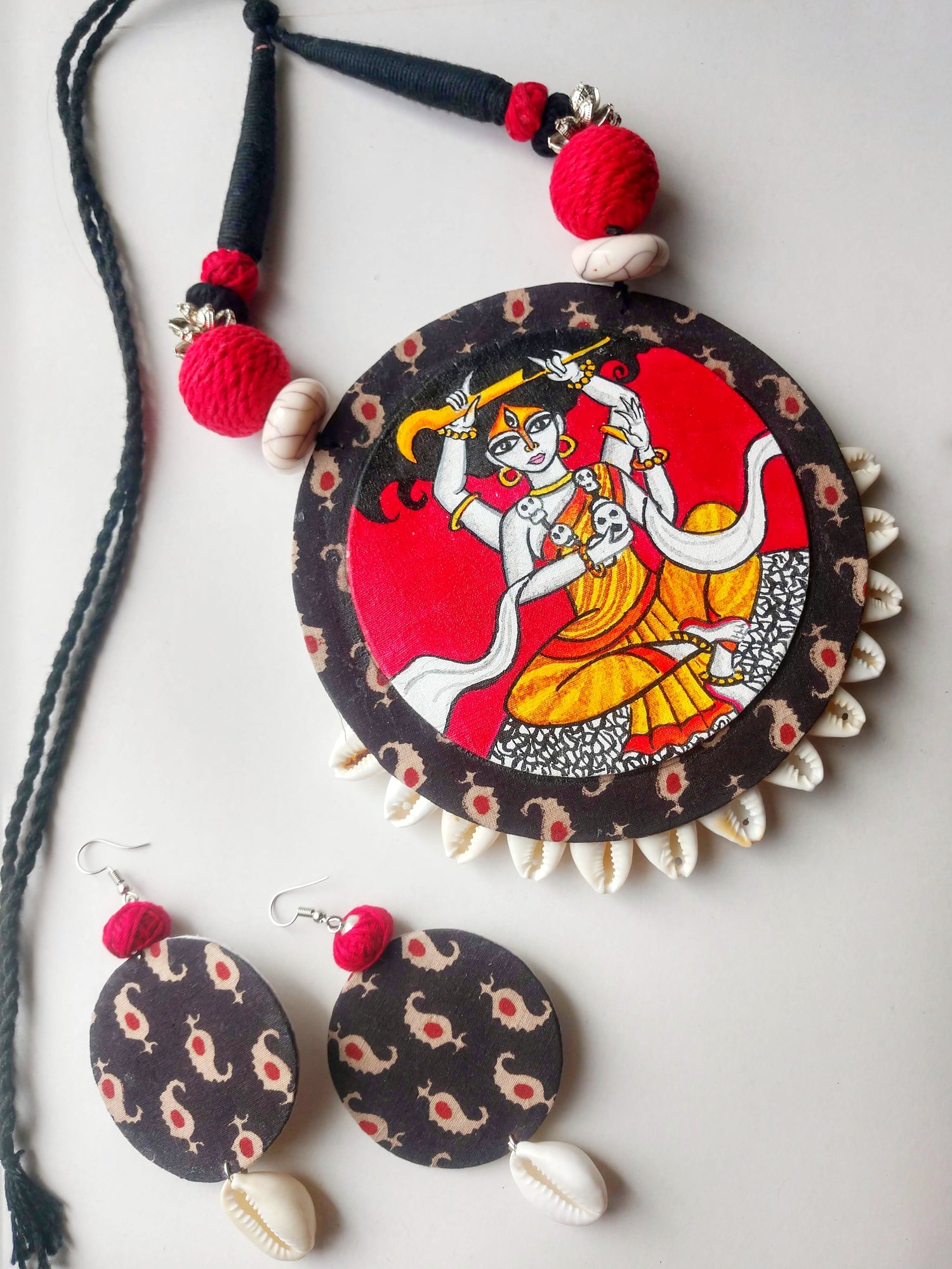 Artisan fabric necklace and earrings featuring handcrafted red and black design with traditional artwork and shell accents