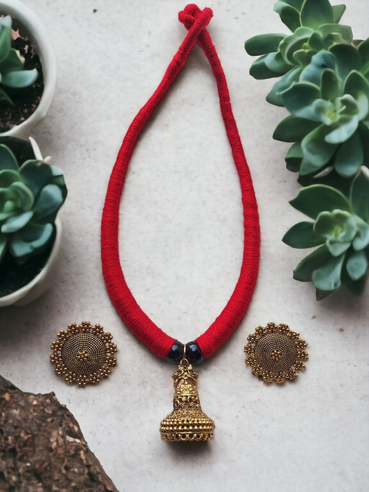 Introducing our stunning Red and Gold jewelry set, perfect for adding a touch of elegance to any outfit. Handmade with care, this set features a Jhumka pendant style fabric choker, which is ideal for the upcoming festive season. The bold red fabric adds a pop of color, while the intricate golden metal jhumka style pendant adds a touch of sophistication. It's the perfect combination of traditional and modern design. Make a statement at your next event with this breathtaking jewelry set.