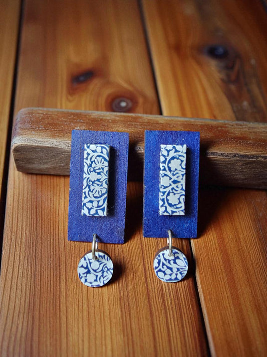 Pair of earrings with blue and white patterns on a wooden surface