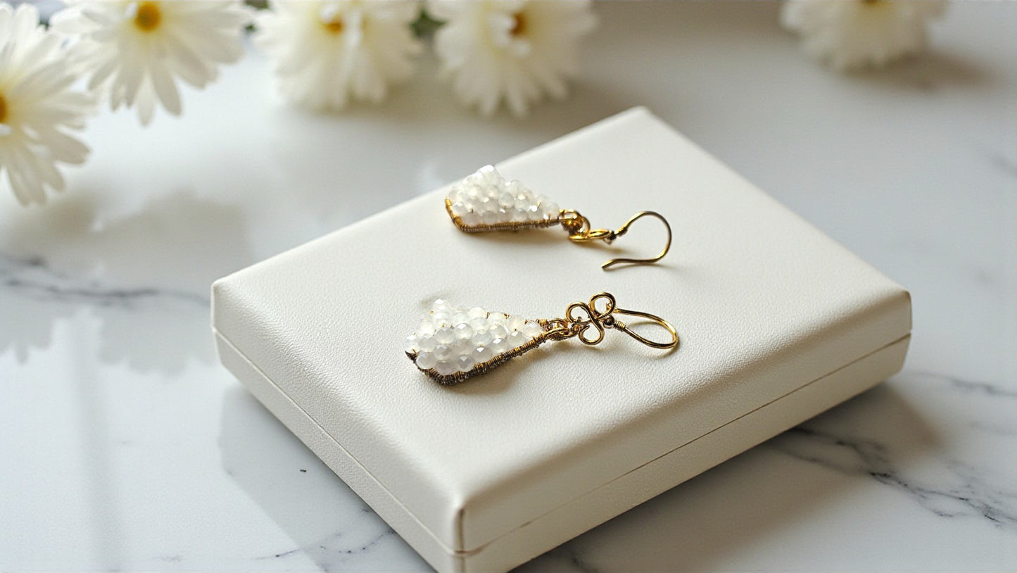 Pearl earrings on a white jewelry box with flowers in the background