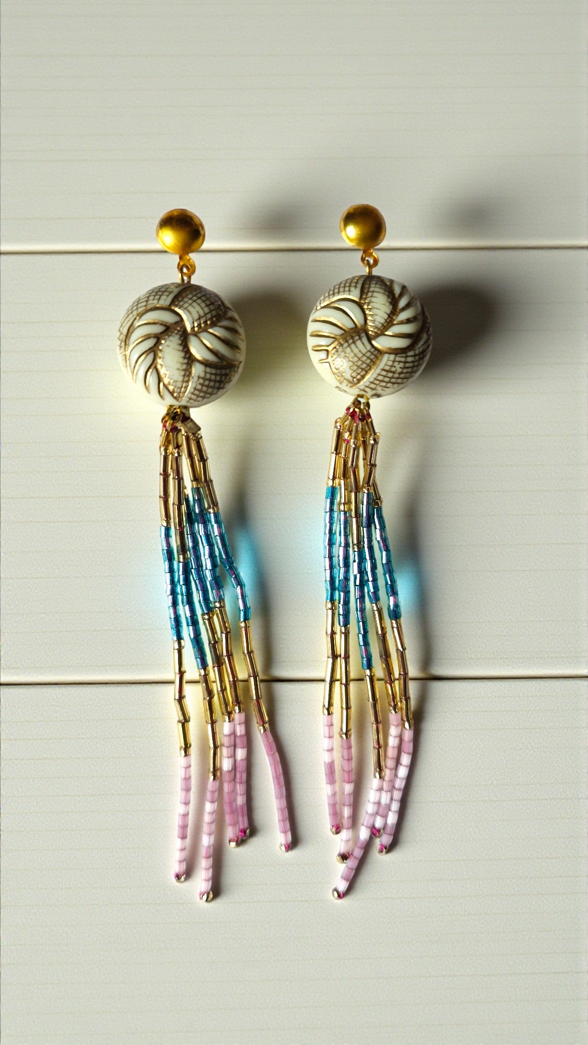 Beaded earrings with colorful tassels on a light gray background