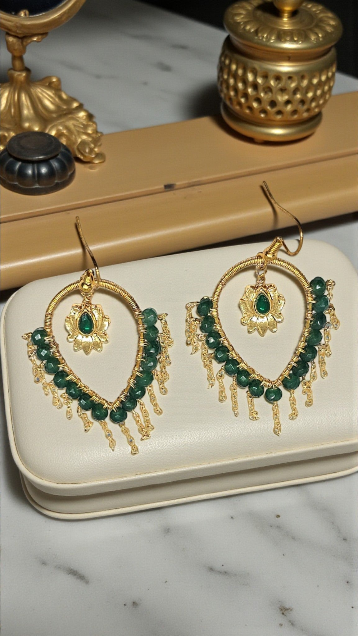 Handcrafted gold-tone hoop earrings with emerald green beads, lotus charm, and cascading chain tassels