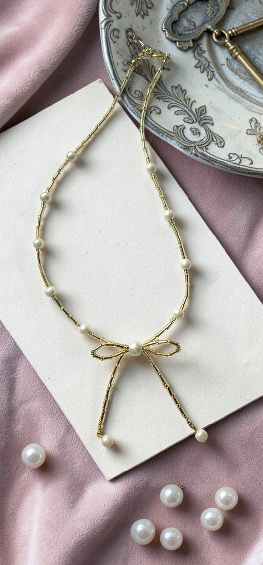 Pearl necklace with a bow on a pink fabric background