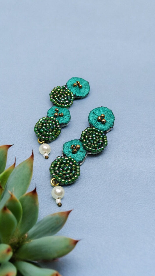Elevate your style with our Aranya Embroidery Earrings, crafted from luxurious cotton thread and dazzling seed beads in a rich, verdant green hue. Indulge in the elegance and exclusivity of these fabric earrings, perfect for the fashion-savvy connoisseur.