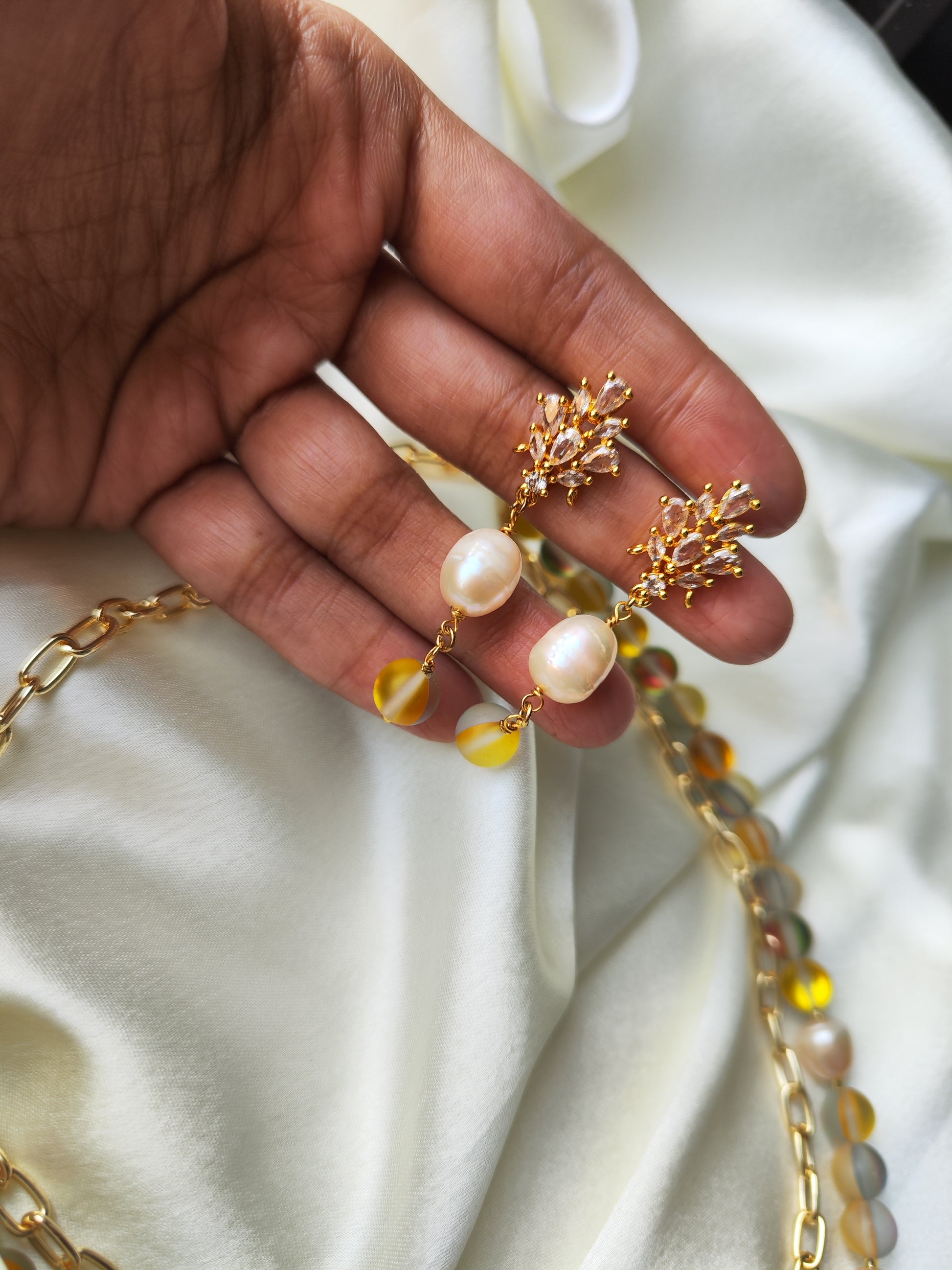 Add some shimmer to your look with the Juliet Beaded Jewelry set. Featuring mother of pearl beads, anti tarnish chains, and Yellow aura beads with CZ charms, this set is both stylish and durable. Shine bright with this unique and playful accessory. (No more jewelry-tarnishing woes for you!)
