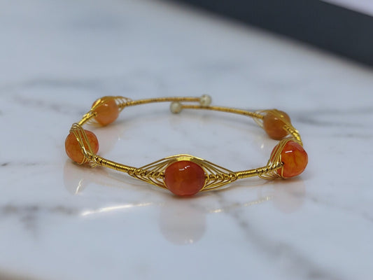 <p data-mce-fragment="1">Add a pop of color and style to any outfit with the playful Clarissa Wire Wrap Bracelet. Featuring vibrant orange Agate beads wrapped in golden wire, this bracelet is adjustable for the perfect fit. Accessorize with a touch of quirky charm!</p>
