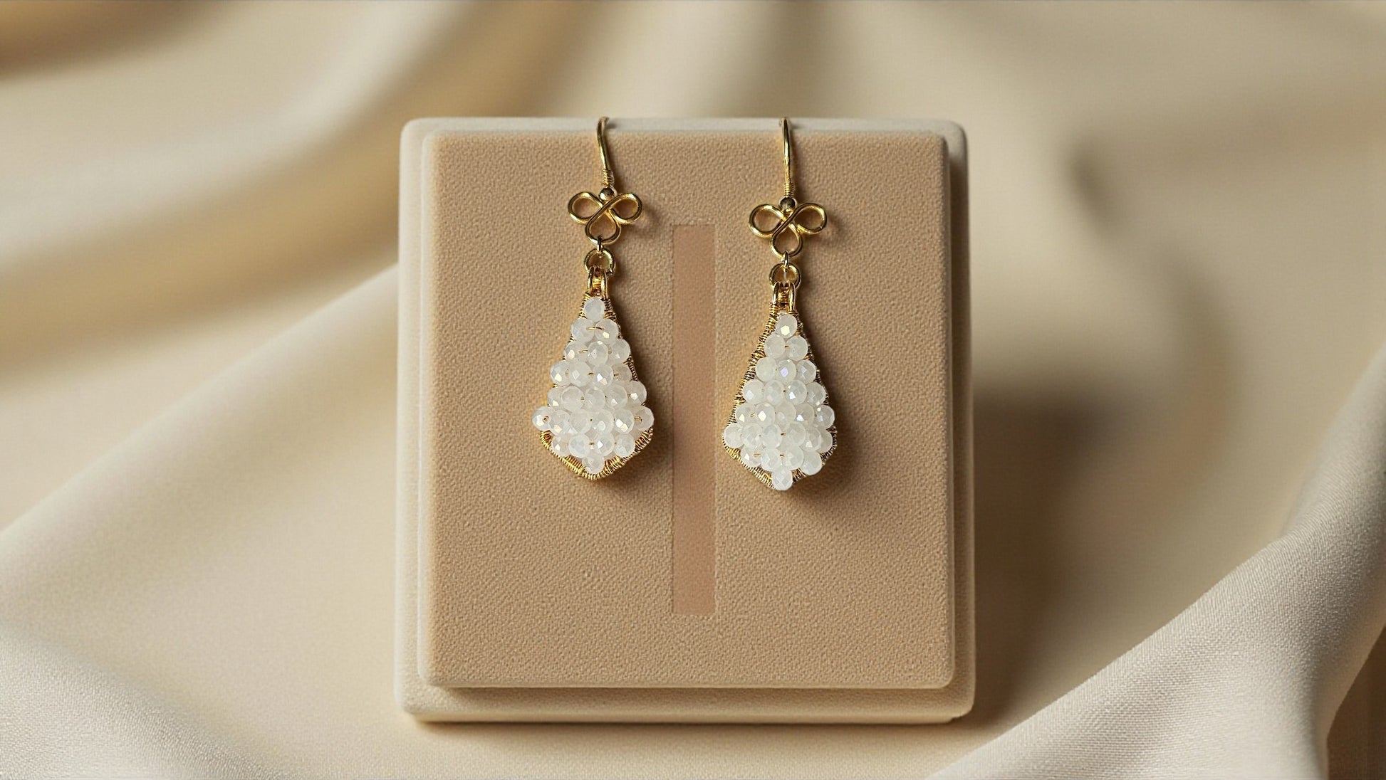 Aahana white bead wrap earrings on a display stand, featuring elegant teardrop shapes